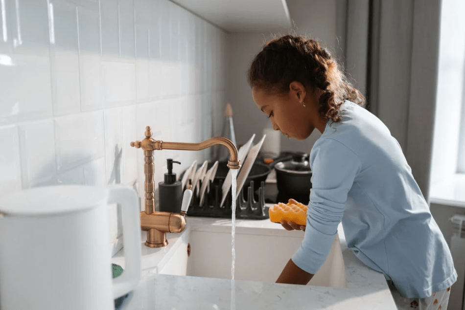 Adolescente lavando platos en un fregadero, ¿por qué tener un lavavajillas cuando tienes hijos?