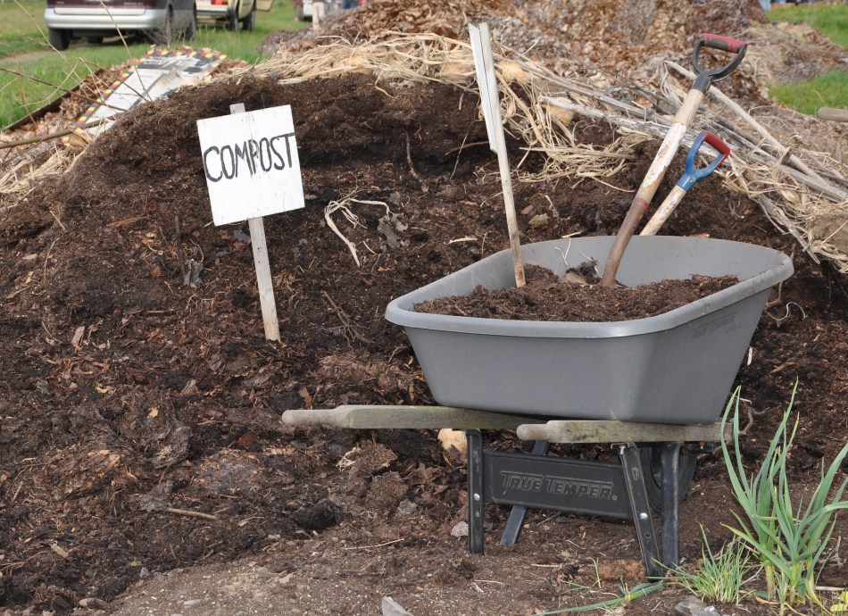 Carretilla con palas junto a una pila de compost pila de compost 