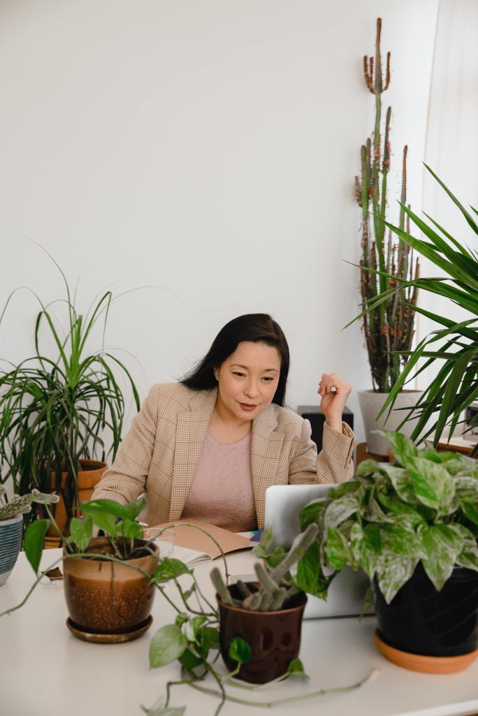 Persona en un escritorio rodeada de plantas.
